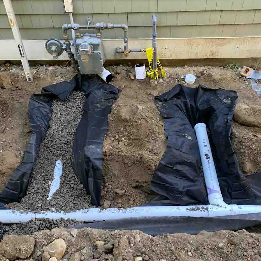 Gas meter installation with underground pipes and gravel.