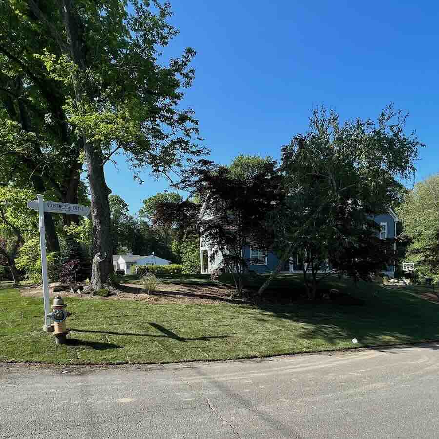 Suburban home with trees and street sign.