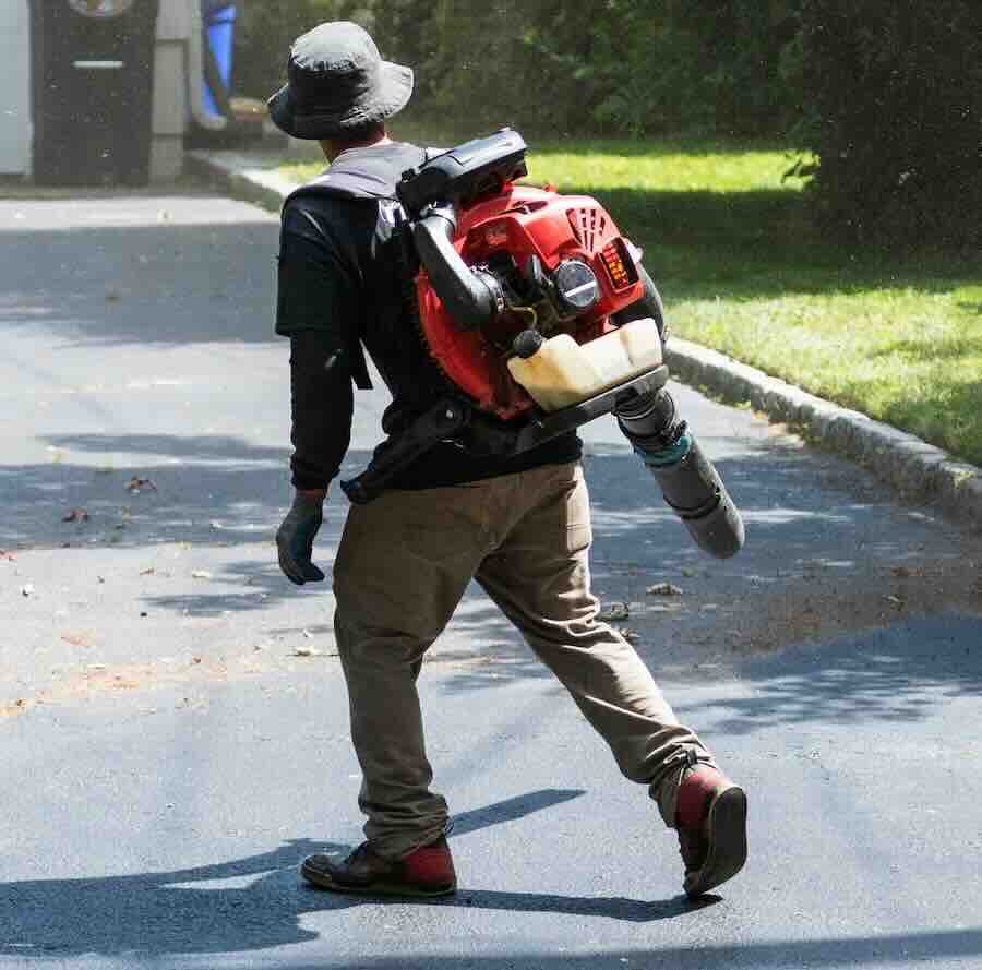 Man using backpack leaf blower on driveway